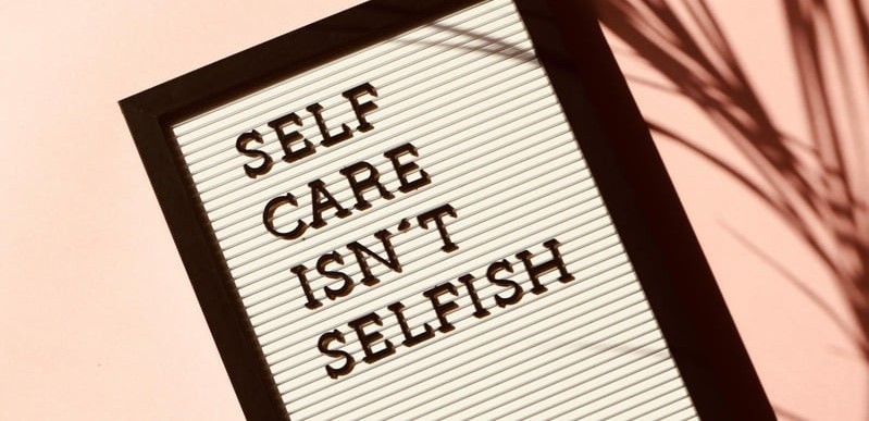 Self-Care and Mental Health Awareness in the Workplace Sign reading “Self Care Isn’t Selfish,” representing workplace wellness workshops that promote self-care and mental health.