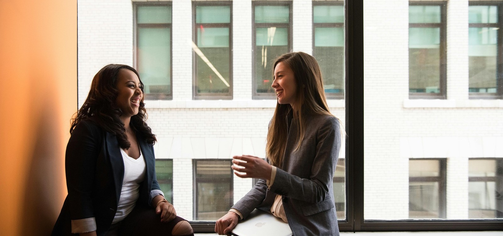 Workplace Wellness Support Conversation Two professionals having a supportive conversation in an office setting, reflecting employee wellness and workplace mental health support.